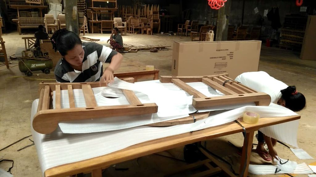 Indonesian workers packing teak wood furniture for export