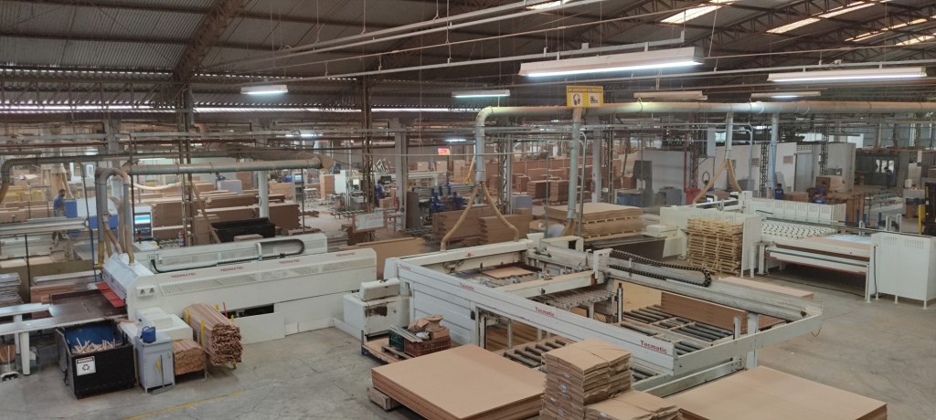 Modern Brazilian furniture manufacturing plant with automated Tecmatic machines and wood panels in production — Vista Furniture Co.