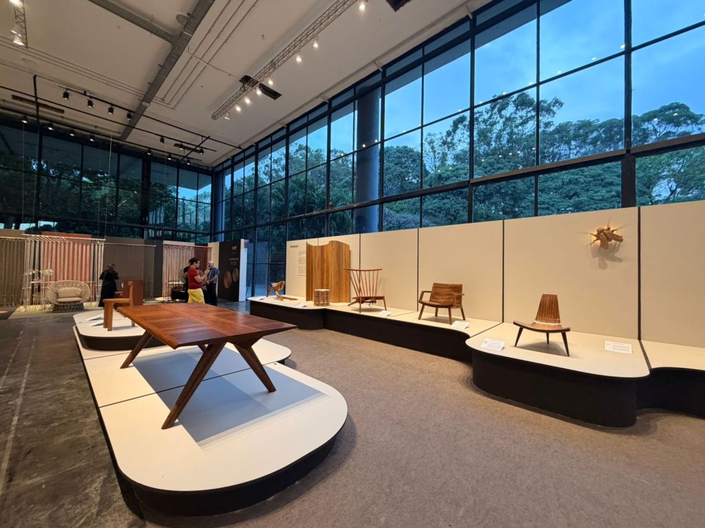 Brazilian furniture design exhibition at SP-Arte São Paulo with park view through glass facade at Bienal Pavilion.
